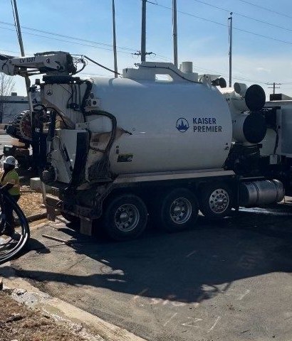 Hydrovac boom deployed over an excavation with hoses run to the curb line