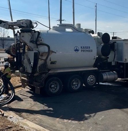 Boom articulated over the dig with suction hoses run out across the asphalt